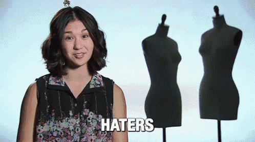 a woman is standing in front of mannequins and says haters .
