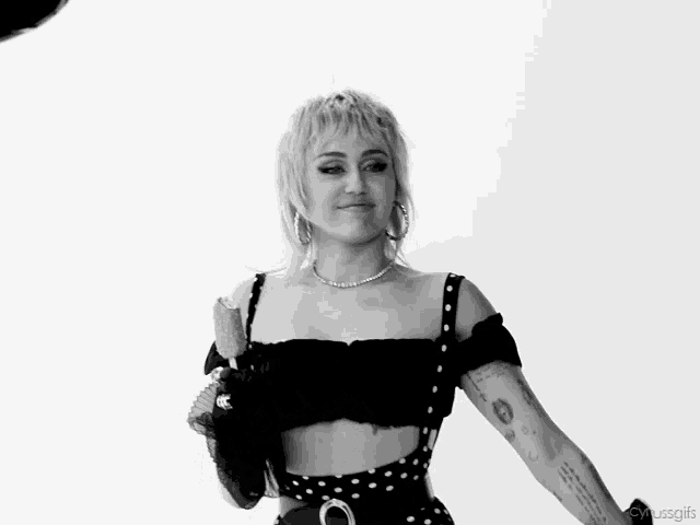 a woman in a polka dot dress is smiling with her arms in the air