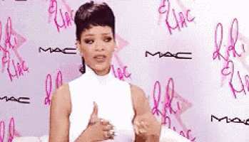 a woman in a white top is giving a thumbs up in front of a mac wall .