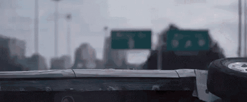 a car is laying on its side on a highway with a city in the background .