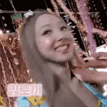 a woman is smiling and looking at the camera while standing in front of a water fountain .