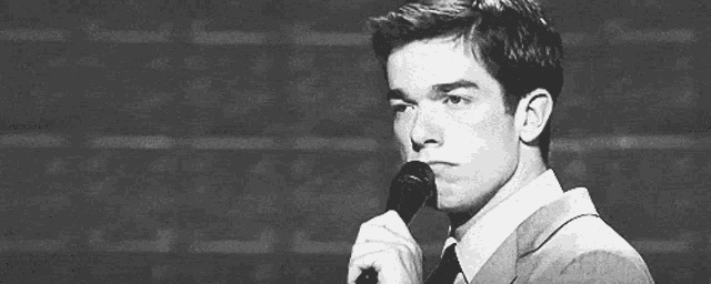 a man in a suit and tie is holding a microphone in front of him .