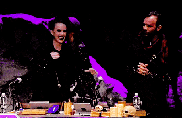 a group of people are sitting at a table with a purple background