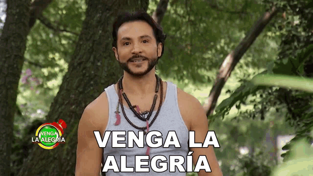 a man stands in front of a tree with the words venga la alegria above him