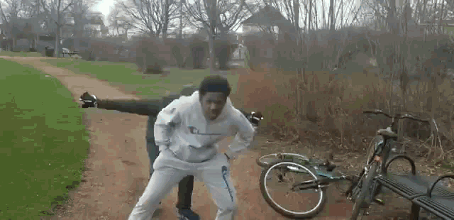 a man is standing next to a bike on a dirt road .