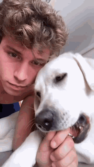 a man laying on a bed with a white dog on his lap
