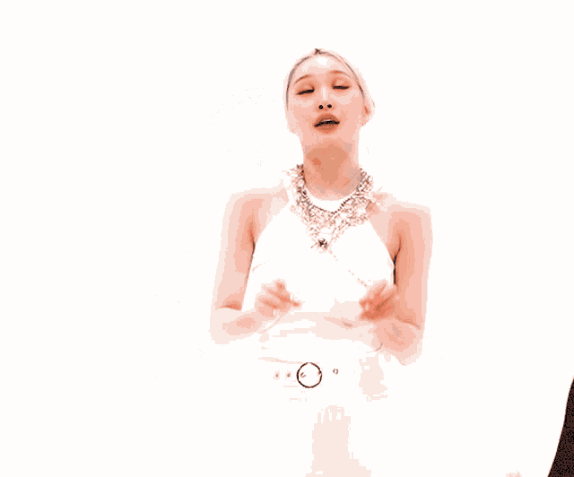 a woman wearing a necklace and a white top