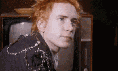 a man with red hair is looking at a television .