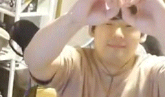 a man is making a heart shape with his hands while taking a selfie .