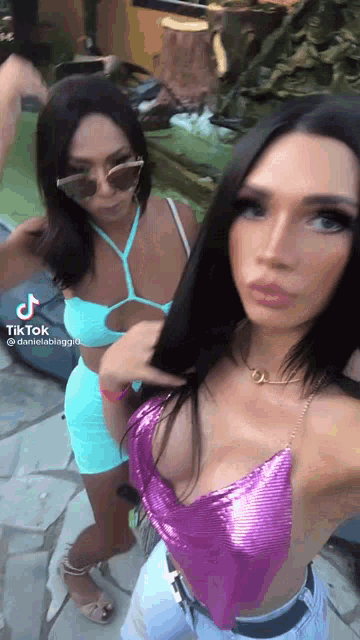 two women are standing next to each other in front of a pool .