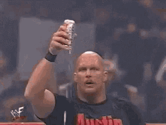 a wrestling wrestler is drinking from a can while holding a microphone .