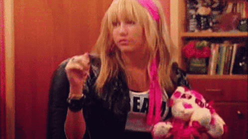 a girl is sitting in a chair holding a stuffed animal and smoking a cigarette .