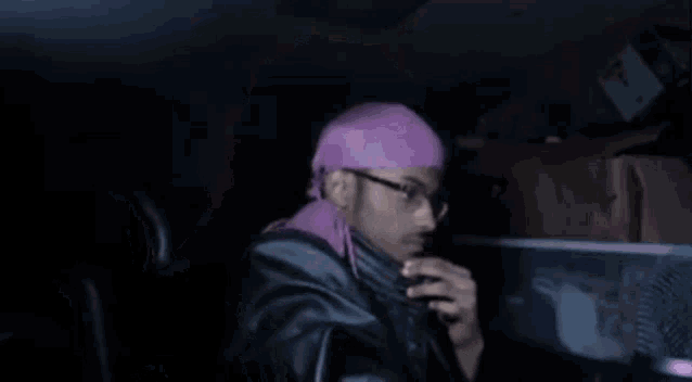 a man wearing glasses and a pink headband is sitting in a car .