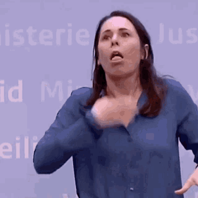 a woman in a blue shirt is making a funny face in front of a sign that says minister