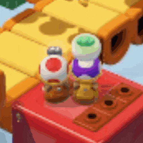 two toads are sitting on top of a red box with holes in it
