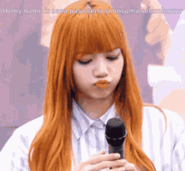 a woman with long red hair is holding a microphone and making a funny face