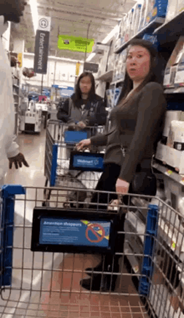 a woman is pushing a shopping cart in a walmart aisle