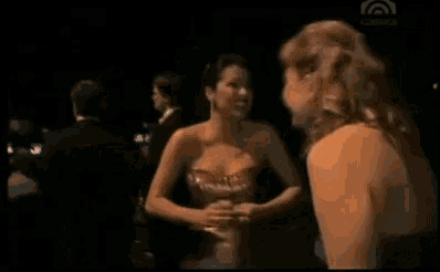 two women in dresses are standing next to each other in a dark room