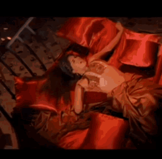a woman is laying on a bed covered in red sheets .