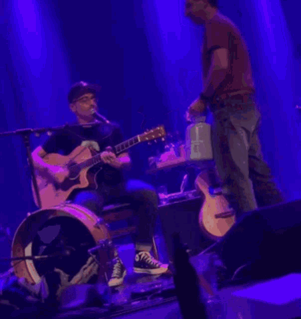 a man playing a guitar and another man playing drums on stage