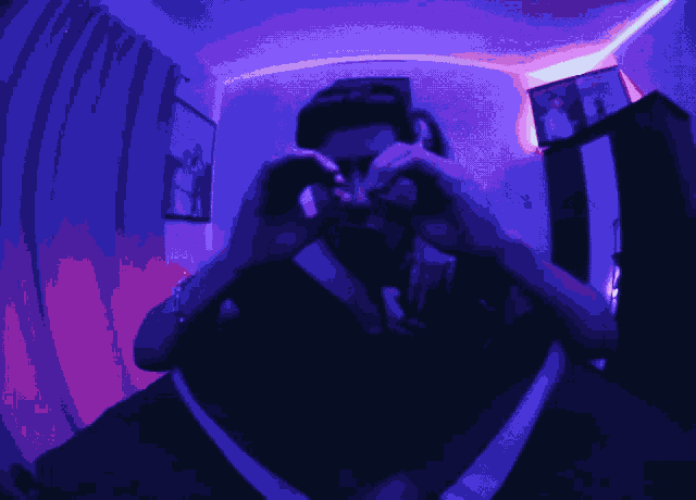 a man is taking a picture of himself in a dark room with purple lights
