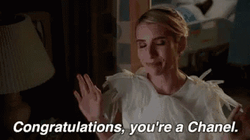 a woman in a white dress is waving her hand and saying `` congratulations , you 're a chanel '' .