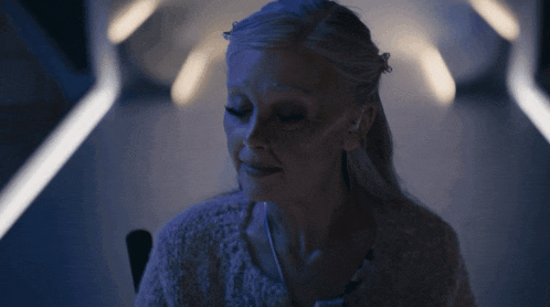 a woman in a white sweater holds her hands together