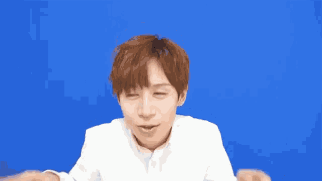 a young man in a white shirt is making a funny face