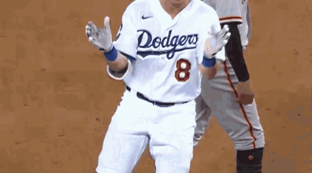 a baseball player in a dodgers uniform is standing next to another player .