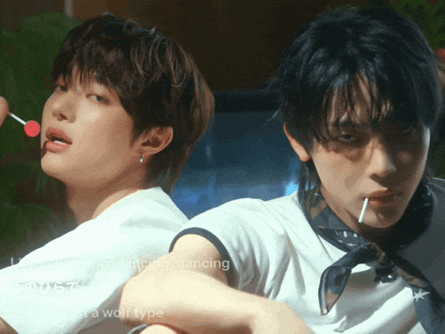 two young men are dancing and one is holding a lollipop