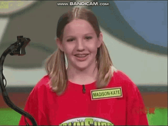 a young girl wearing a red shirt with a name tag that says madison kate