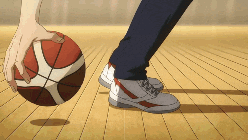 a person is holding a basketball on a wooden floor