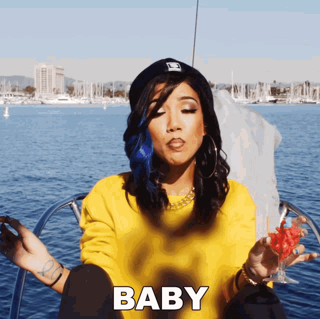 a woman in a yellow sweater is sitting on a boat and says baby
