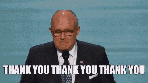 a man in a suit and tie is giving a speech and saying thank you .
