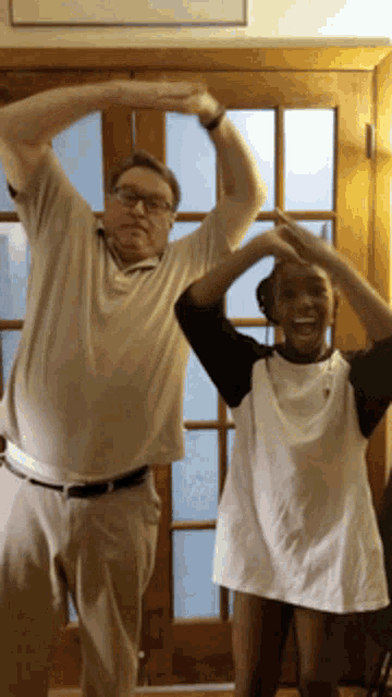 a man and a woman are making a heart shape with their arms