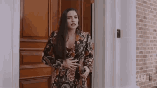 a woman is standing in front of a door holding her belly .