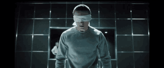 a man wearing a blindfold is standing in front of a mirror