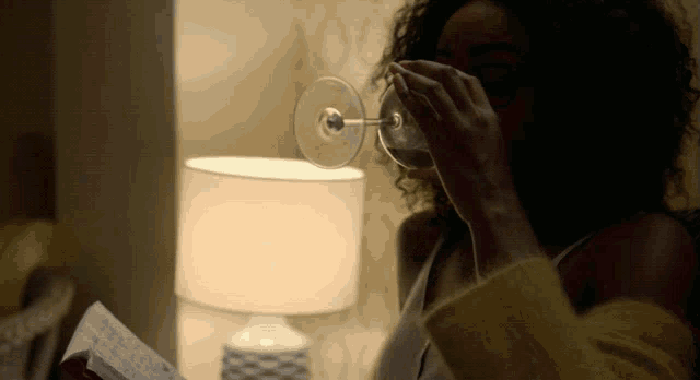 a woman is drinking a glass of wine while reading a book