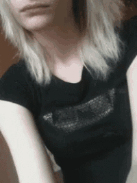 a woman with blonde hair is wearing a black shirt and taking a picture of herself .