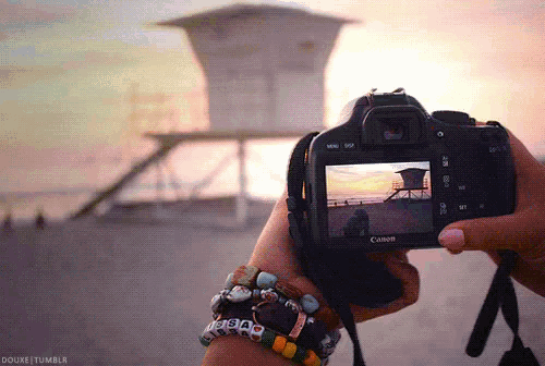 a person is holding a canon camera in their hand