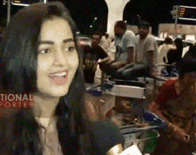 a woman is smiling in front of a crowd and the word national is on the bottom