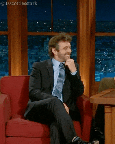 a man in a suit and tie is sitting in a red chair and says those french