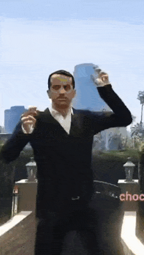 a man in a black sweater and white shirt is dancing in front of a city skyline ..