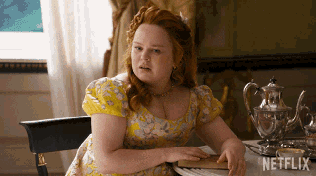 a woman in a yellow dress is sitting at a table with a netflix logo on it