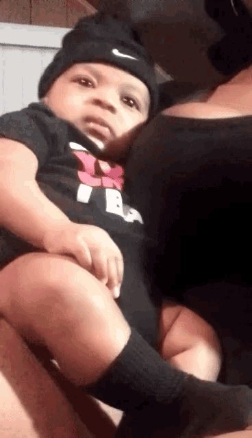 a baby is being held by a woman wearing a nike hat