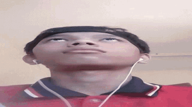 a young boy wearing headphones and a headband is looking up at the sky .