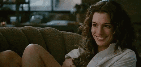 a woman is sitting on a couch wearing a white robe and smiling .