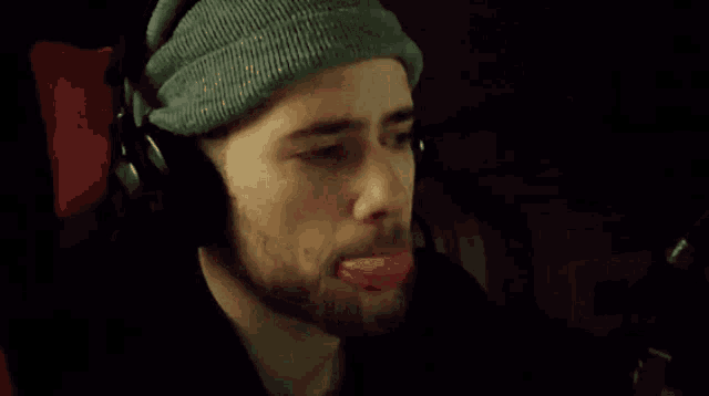 a man wearing headphones and a beanie is making a funny face