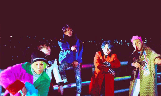 a group of people are standing in a dark room and one of them is wearing a green jacket