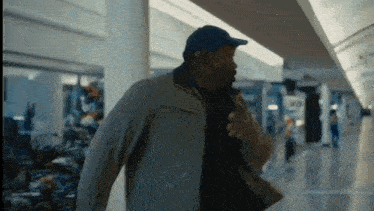 a man wearing a blue hat and a jacket is walking through a mall